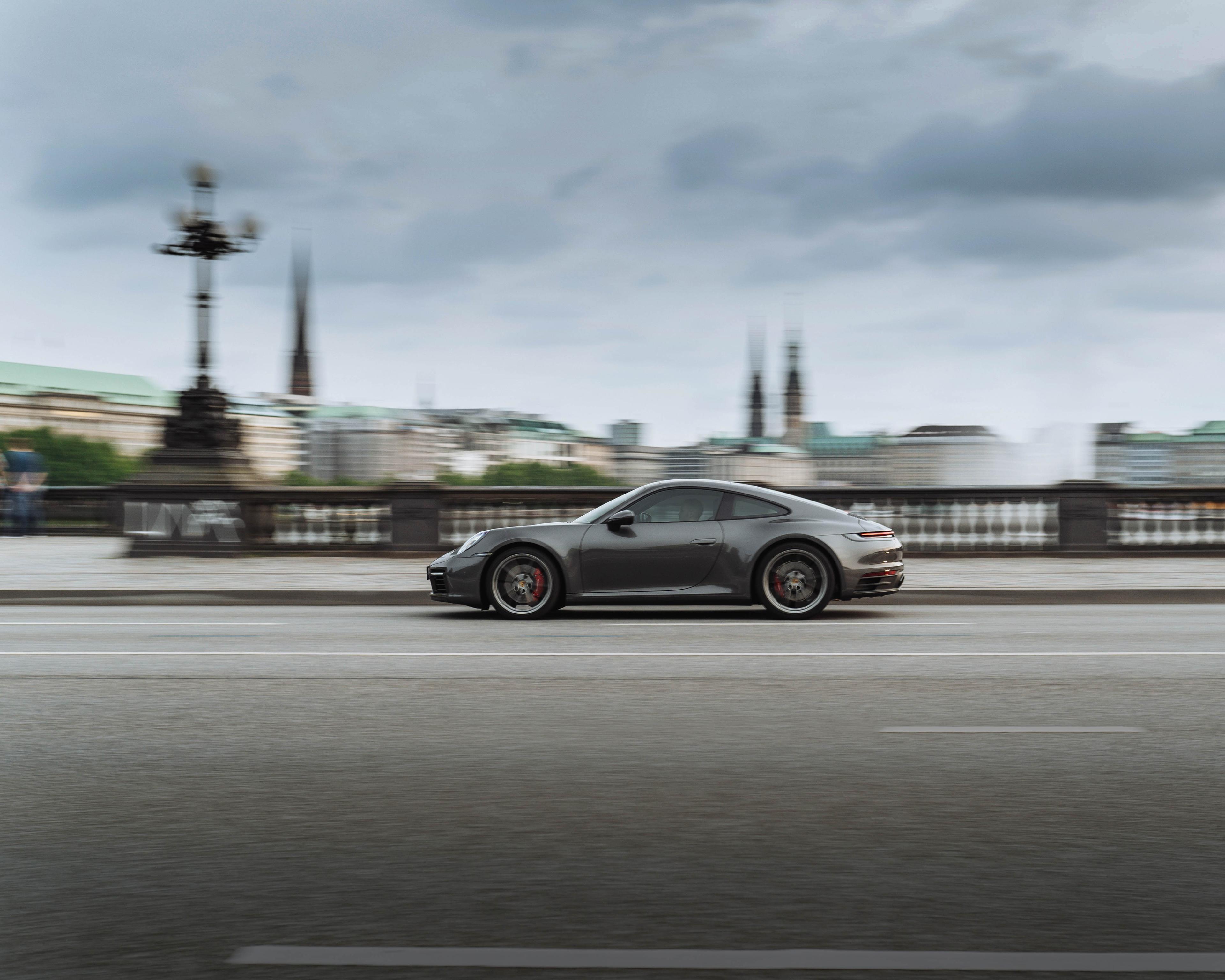 A couple in a hotel room watching a Porsche in the street